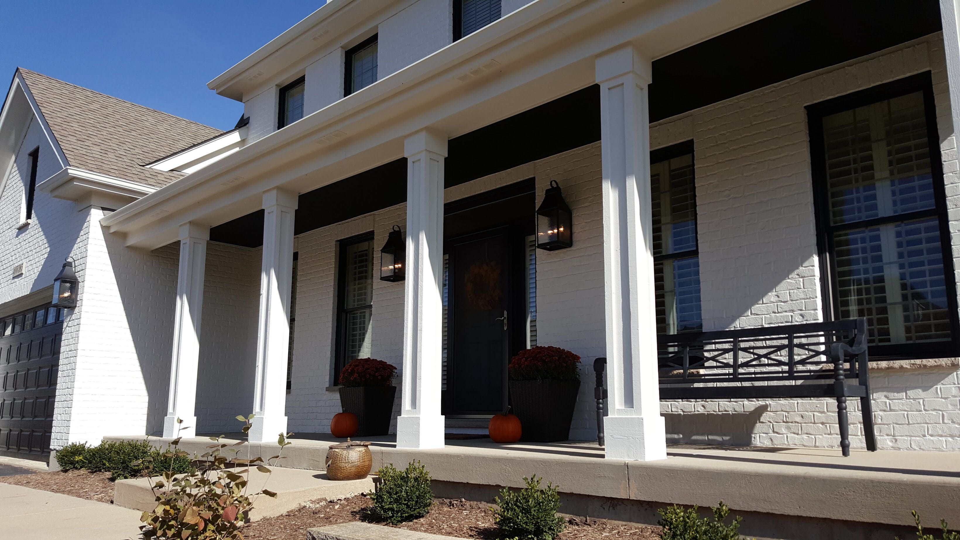 White brick house porch with pumpkins
